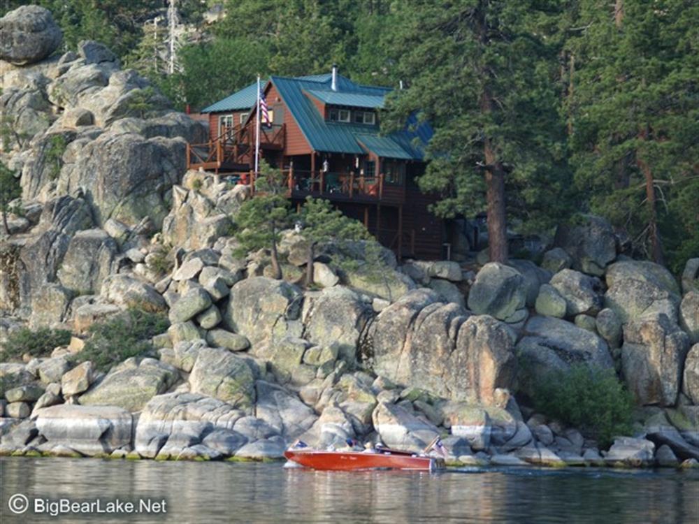 Antique wooden boat passes below a historic cabin
